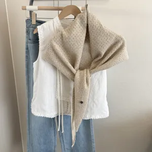 Beige knitted hollow shawl paired with white lace top and blue jeans, chic autumn winter cape.