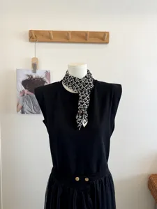 Gedetailleerd overzicht van een zwart-witte jacquard driehoekige sjaal met houten knoop.