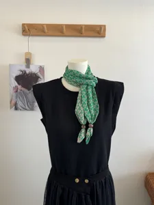 Groene gedrukte driehoekige sjaal met houten kraalknoppen, retro contrasterend bloemendesign.