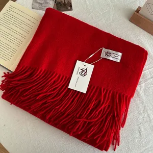Solid red wool scarf with classic fringe design, featuring brand tag, soft winter accessory detail.