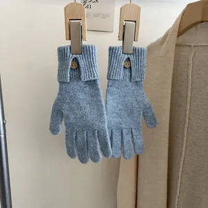 Detail shot of solid color knitted touchscreen gloves with single button cuff for women winter.