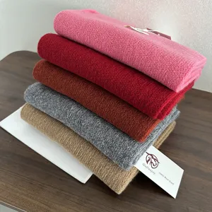 Detailed view of stacked colorful wool scarves showcasing texture, softness and fine knit detail.