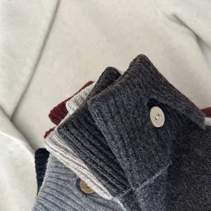 Winter solid color knitted gloves detail view, soft thermal wool fabric with cute wooden button design.