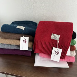 Close-up detail of soft 100% wool knit scarves stacked in various vibrant winter colors.
