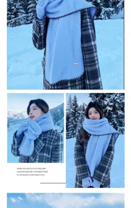 Close up of soft blue winter scarf with brown stitching in snowy mountain outdoor scene.