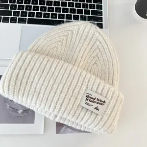 Close-up shot of ribbed knit wool beanie winter hat detail showing woven patch label.