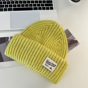 Close-up detail of the cozy green knit beanie showing soft textured yarn and brand label patch.