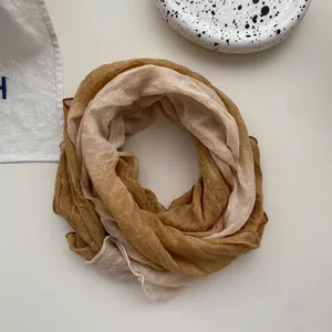 Gradient linen cotton scarf detail, wrinkled texture beige and brown, soft cozy fabric.