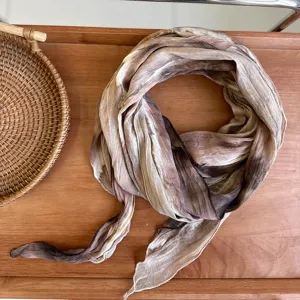 Detailed shot of a Japanese style tie-dye linen scarf with natural crinkle texture and earthy tones.