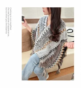 Detailed shot of ethnic style knitted poncho shawl with fringe, cozy lifestyle indoor.