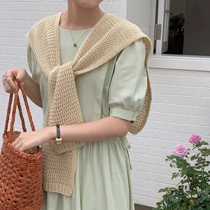 Close-up view of a sweet hollow-out knitted shawl paired with an elegant green dress detail.