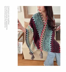 Close-up detail of ethnic style knitted poncho with colorful zigzag pattern and tassels.