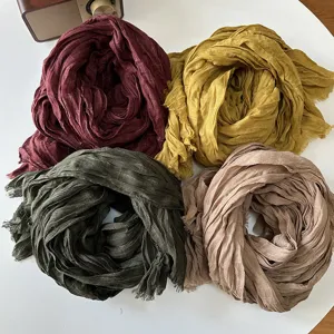 Detailed view of four colorful cotton linen pleated plaid scarves neatly arranged on a white table.