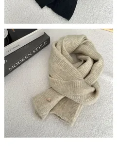 Detailed close-up view of soft beige knitted scarf featuring ribbed texture and button.