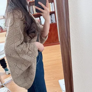 Detailed view of a stylish hollow out knitted cardigan cape in a chic beige tone, perfect for wear.