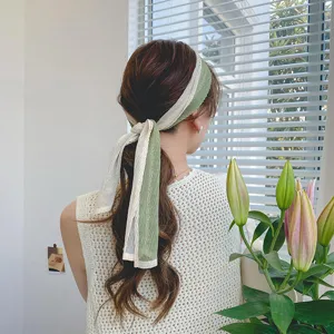 Elegant pleated hair scarf detail shot, green and white color-blocking ribbon for styling hair.