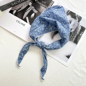 Close-up of the blue floral cotton-linen triangular headscarf featuring delicate white lace trim.