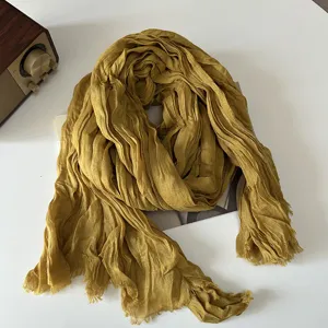 Detailed shot of the mustard yellow crinkled linen scarf, showing retro texture and soft fabric.