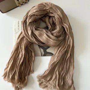 Detailed close-up shot of a beige crumpled linen scarf on a white table with radio.