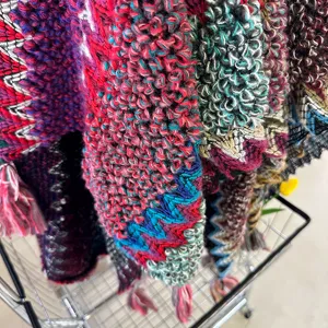 Ethnic knit shawl cape detail, vibrant colors, woolen texture, boho winter travel look.