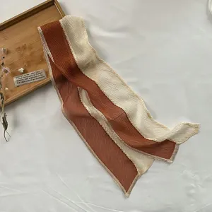 Pleated color-block hair scarf detail, elegant two-tone brown and beige silk ribbon.