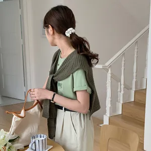 Detailed view of women hollow out knit shawl worn over casual green tee indoor lifestyle shot