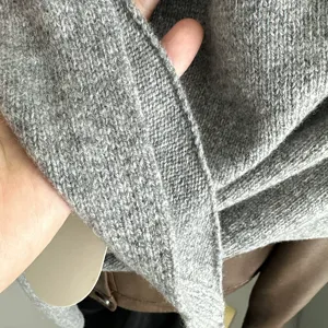 Primo piano di una sciarpa triangolare in maglia di pura lana grigia dalla trama fine.