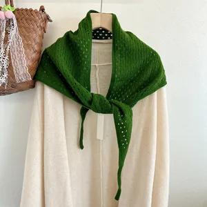 Green knitted triangular scarf detail, hollow wool shawl closeup, winter warm fashion accessory.