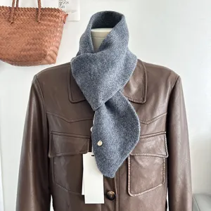 Primo piano dettagliato della sciarpa incrociata in maglia grigia su manichino con giacca in pelle.