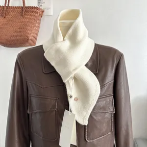 Vista dettagliata di una sciarpa incrociata in maglia crema su una giacca di pelle.