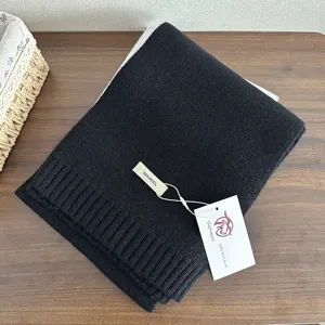 Black knit wool scarf detail showing soft texture and hanging tag. Perfect for winter warmth.