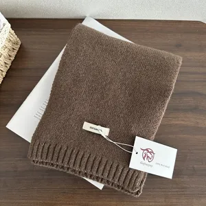 Detailed view of brown 100% wool knitted scarf, showcasing soft texture and quality tags.
