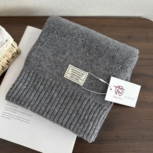 Grey wool knitted scarf detail view, showing soft texture, brand label and winter warmth style.