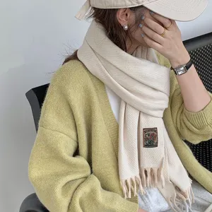 Close-up detail of cozy beige knitted tassel scarf, soft winter warmth and classic design.