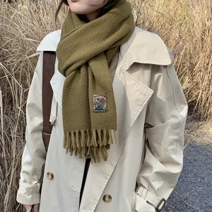 Olive green cashmere-feel winter scarf detail showing cozy texture and woven tag design.