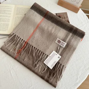Detailed shot of a cozy plaid wool scarf with fringes, displayed on a wooden table setup.