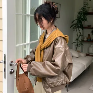 Brown PU leather jacket detail view with knitted yellow scarf in interior lifestyle