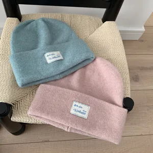 Close-up detail of soft wool blend knitted beanie hats in blue and pink with fabric label.