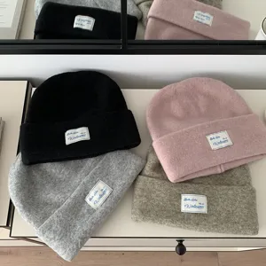 Autumn winter knitted woolen beanie hat detail, warm fleece slouchy cap with cloth label.