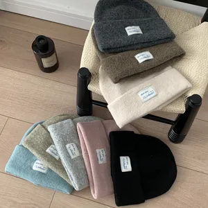 Detail shot of multi-color knitted beanie hats with cloth labels, warm autumn and winter styles.