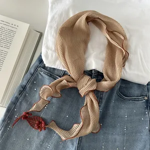 Detailansicht des geknitterten khakifarbenen kleinen Halstuchs mit zartem Blatt-Anhänger.