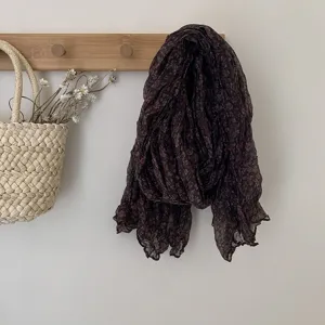Close-up detail of the retro floral wrinkled scarf hanging on wall, showing fabric texture and pattern.
