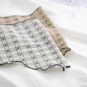 Detail shot of stylish plaid embroidered triangular scarf and hair band in soft fabric.