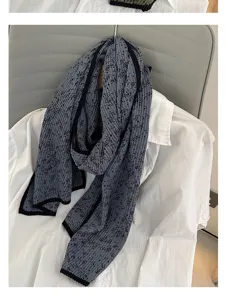 Detail view of the grey floral pleated scarf featuring elegant textured fabric and black hem.
