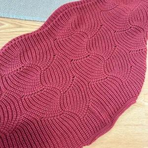 Detailansicht eines dunkelroten Strickschals mit fischschuppen Muster, weich und warm.