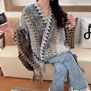 Ethnic style knitted shawl cape for women, cozy winter poncho with fringe and geometric pattern.