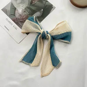 Detail shot of pleated color-block hair bow, showcasing soft fabric texture and elegant design.