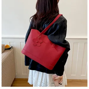 Vista dettagliata della borsa tote in pelle PU rossa con grande capacità e charm floreale.