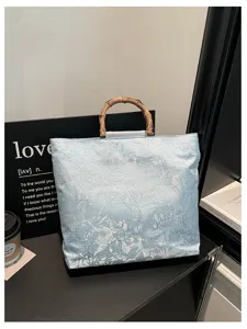 Detailaufnahme der blauen floralen Stofftasche mit natürlichem Bambusgriff und eleganter Textur.