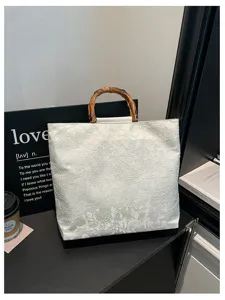 Elegante weiße Stoffhandtasche mit natürlichem Bambusgriff für die tägliche Mode.